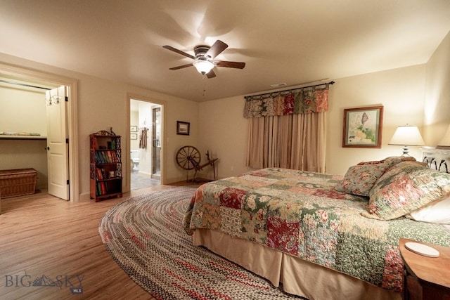 bedroom with a ceiling fan, wood finished floors, visible vents, and connected bathroom