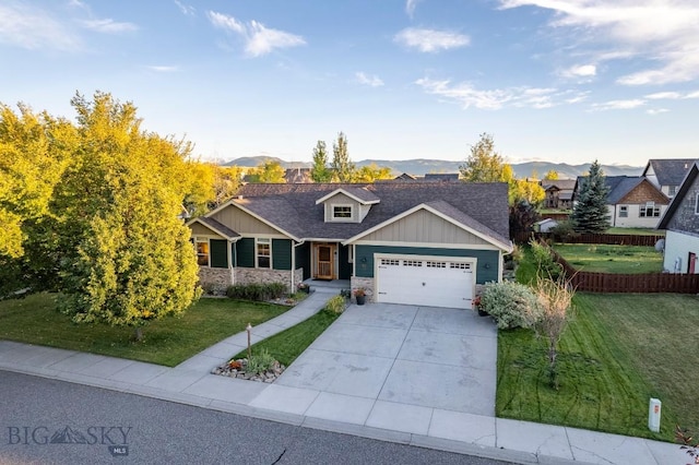 view of front facade featuring an attached garage, concrete driveway, a front yard, and a mountain view