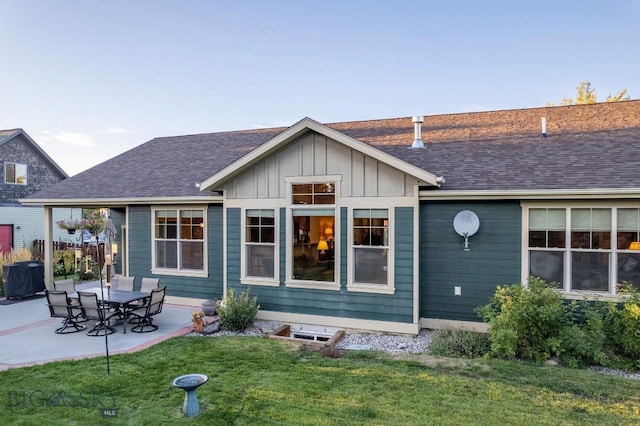 back of property featuring a yard, a shingled roof, board and batten siding, and a patio