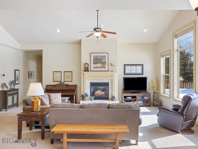 living area featuring light carpet, a ceiling fan, a glass covered fireplace, vaulted ceiling, and recessed lighting