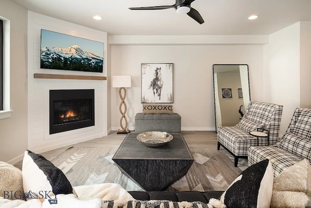 living area with recessed lighting, a ceiling fan, a large fireplace, and baseboards