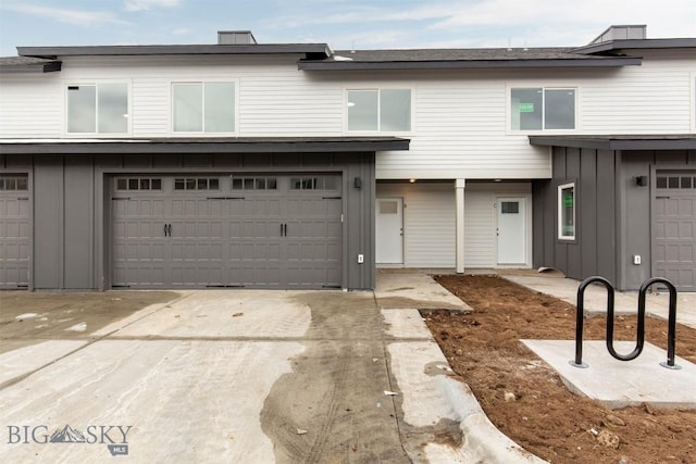 view of property with a garage, board and batten siding, and concrete driveway