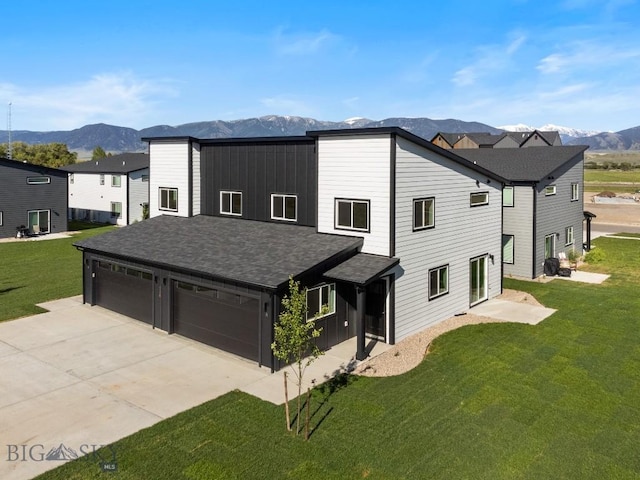 view of front facade with a mountain view, a garage, concrete driveway, roof with shingles, and a front yard