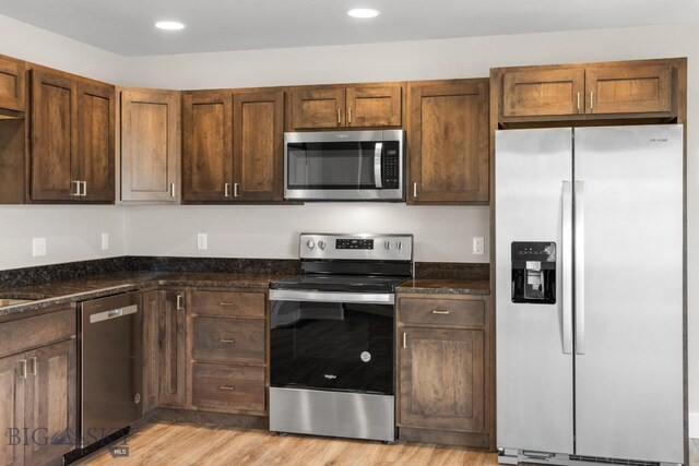 kitchen with stainless steel appliances, recessed lighting, dark stone countertops, and light wood-style floors