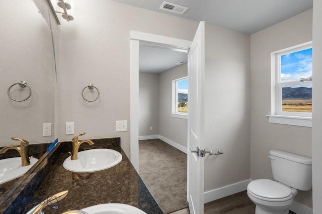 bathroom with baseboards, visible vents, a sink, and toilet