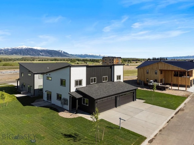 view of front of house with an attached garage, a mountain view, a front lawn, and concrete driveway