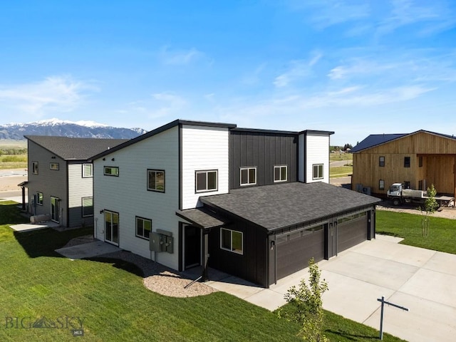 view of front facade featuring driveway, a front lawn, an attached garage, and a mountain view