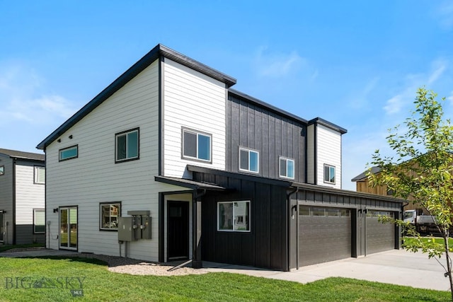 rear view of house with a garage, board and batten siding, and a yard