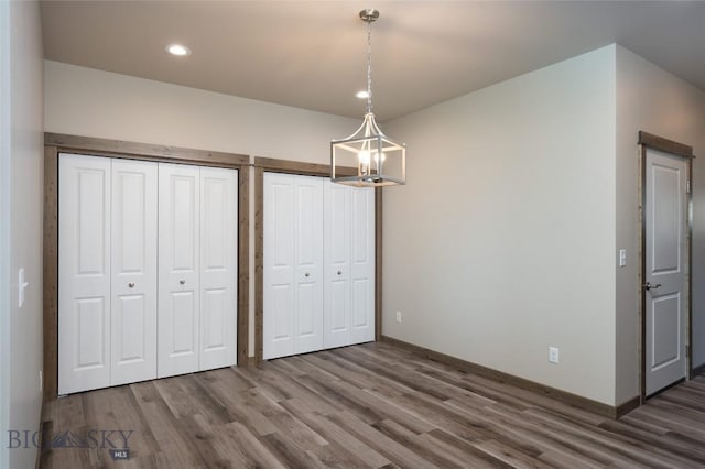 unfurnished bedroom with recessed lighting, wood finished floors, and two closets