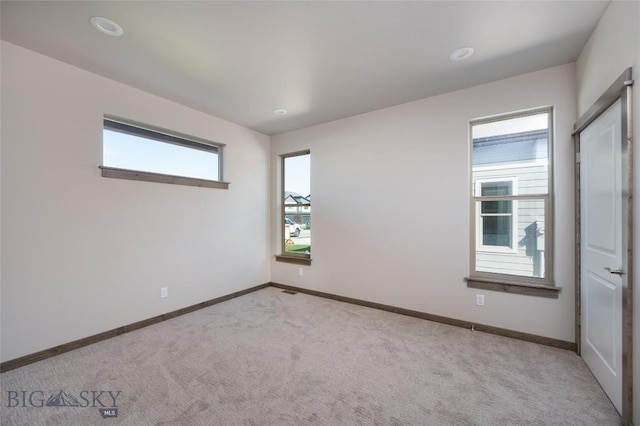 empty room featuring light colored carpet and baseboards