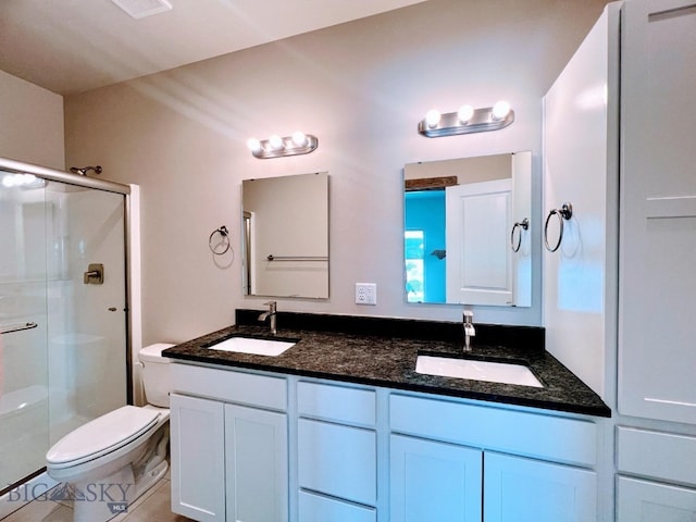 full bathroom with double vanity, a stall shower, a sink, and toilet