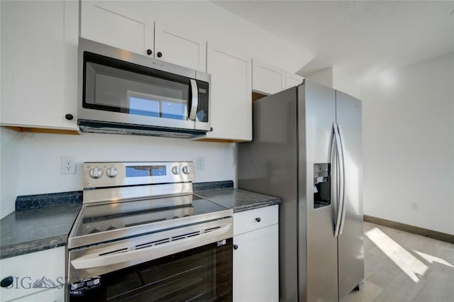 413 Garnier Ave Unit B, Livingston, MT 59047 - kitchen featuring baseboards, stainless steel appliances, dark countertops, and white cabinets