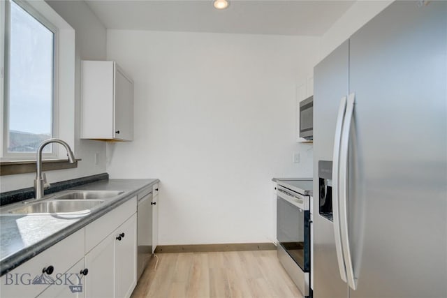 413 Garnier Ave Unit B, Livingston, MT 59047 - kitchen featuring a sink, baseboards, white cabinets, appliances with stainless steel finishes, and light wood-type flooring