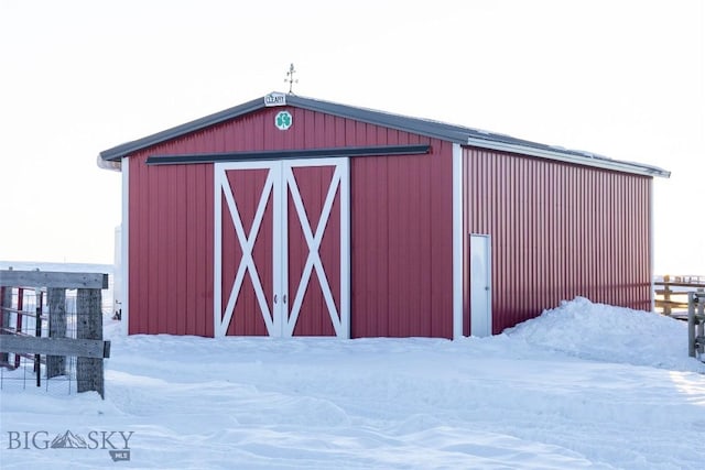 snow covered structure featuring an outbuilding and a barn