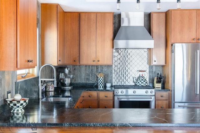 kitchen featuring brown cabinetry, a sink, appliances with stainless steel finishes, wall chimney exhaust hood, and tasteful backsplash