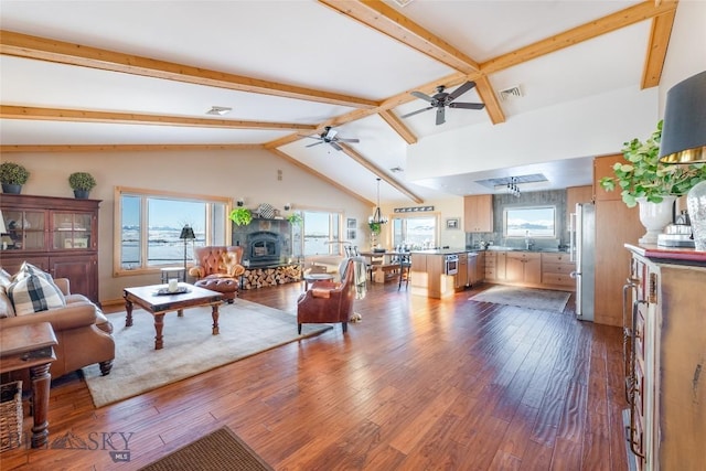 living area with ceiling fan, visible vents, plenty of natural light, and dark wood-style floors