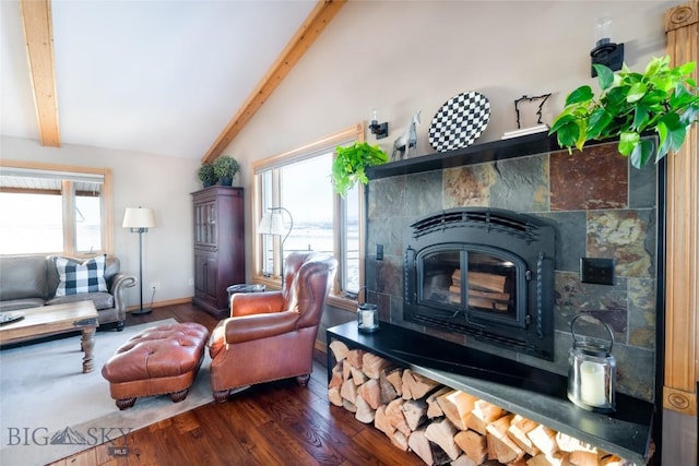 living area featuring a healthy amount of sunlight, a tile fireplace, vaulted ceiling with beams, and wood finished floors