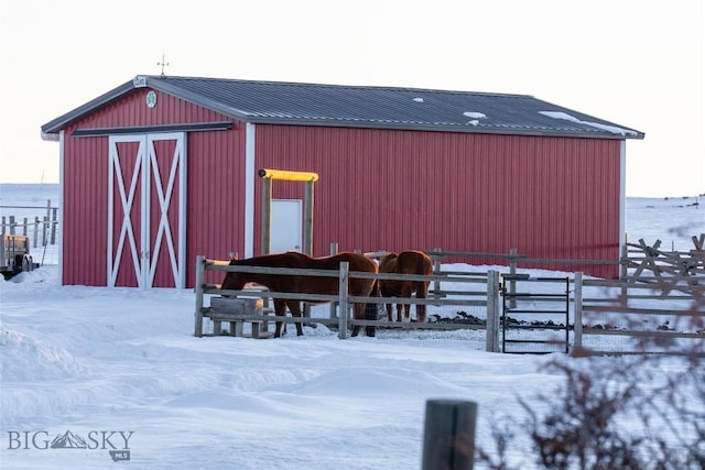 snow covered structure with an outbuilding