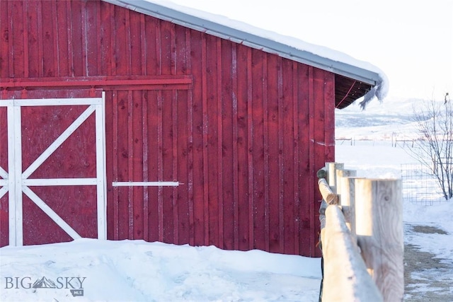 snow covered structure featuring an outbuilding and a barn