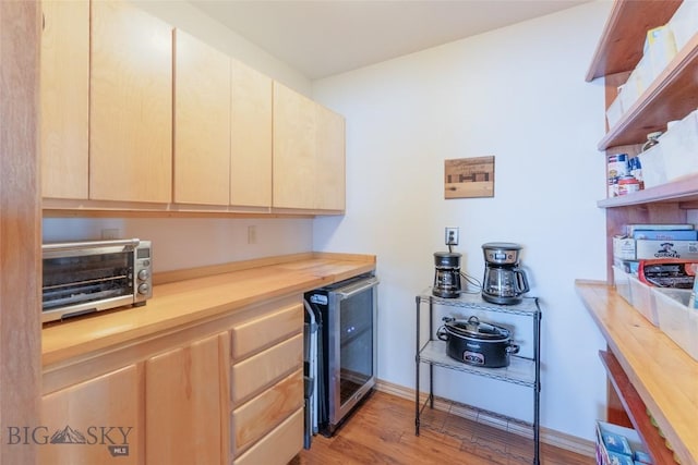 kitchen with wine cooler, light wood-style flooring, butcher block counters, and light brown cabinetry