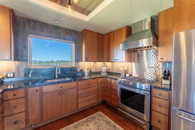 42 Jim Parrent Ln, Big Timber, MT 59011 - kitchen with appliances with stainless steel finishes, wall chimney range hood, a sink, dark wood-type flooring, and dark stone counters