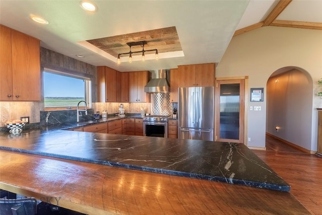 42 Jim Parrent Ln, Big Timber, MT 59011 - kitchen with appliances with stainless steel finishes, wall chimney exhaust hood, dark wood-style floors, arched walkways, and tasteful backsplash