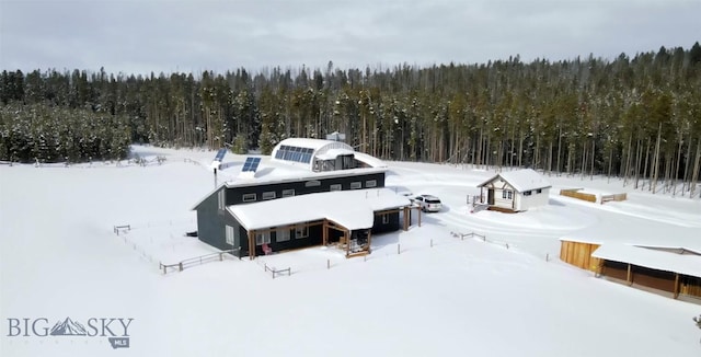 snowy aerial view featuring a wooded view