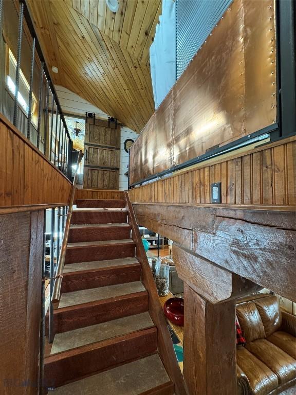 stairway featuring vaulted ceiling, wooden ceiling, and wooden walls