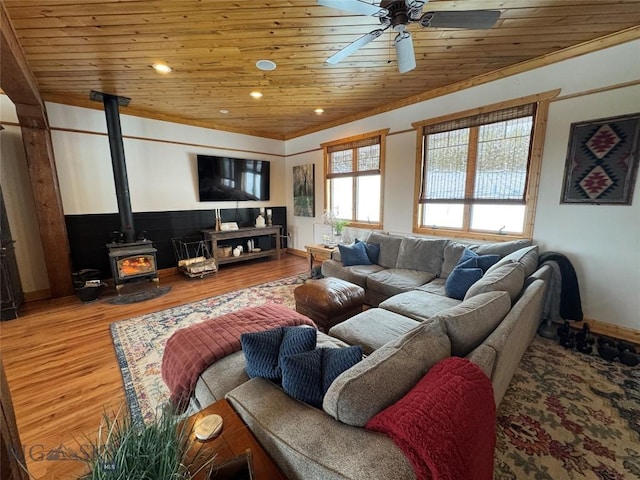 living room with wooden ceiling, ceiling fan, a wood stove, and wood finished floors