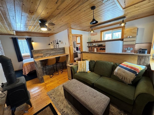 living area featuring wooden ceiling, ceiling fan, a wood stove, and hardwood / wood-style flooring