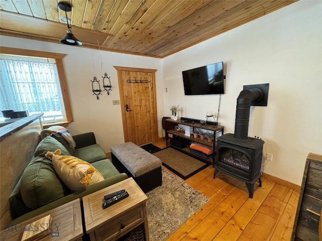 living area featuring attic access, baseboards, wood ceiling, a wood stove, and light wood-style floors