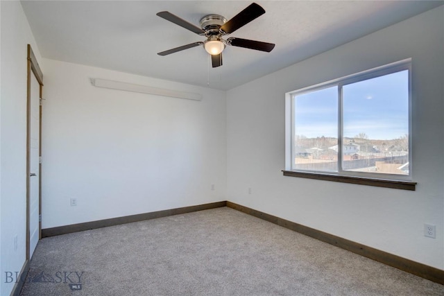 carpeted empty room featuring ceiling fan and baseboards