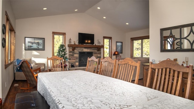 dining space with recessed lighting, high vaulted ceiling, dark wood-type flooring, and a stone fireplace