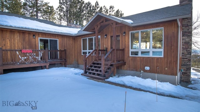 exterior space featuring a shingled roof, a chimney, and a deck