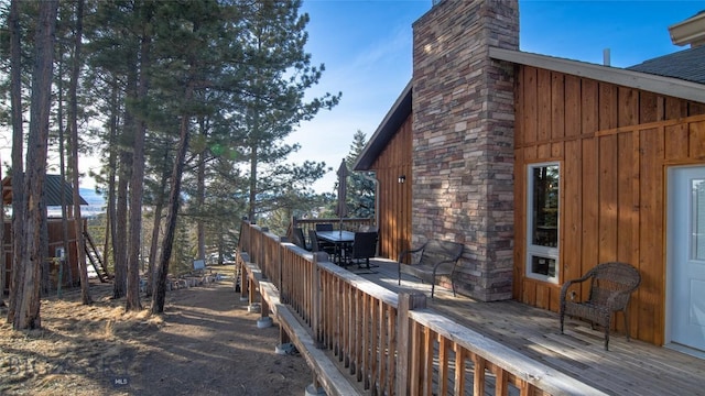 view of side of property with a chimney, a deck, and board and batten siding