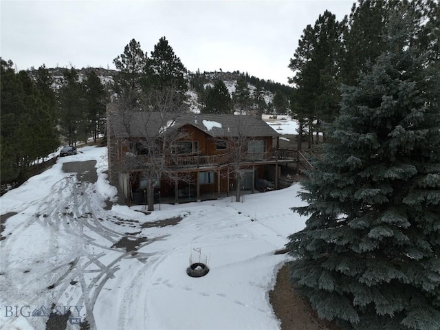 snow covered rear of property featuring stairs and a wooden deck