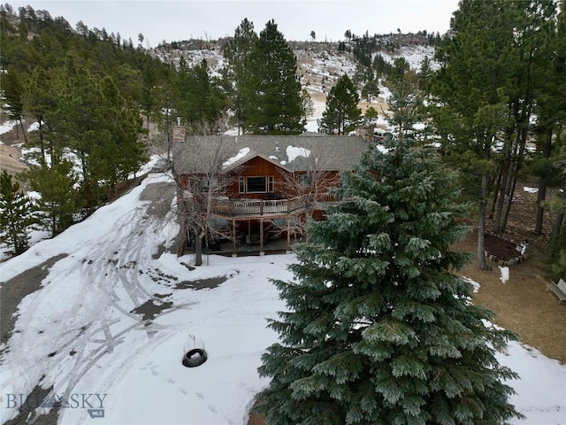 snow covered rear of property featuring a chimney