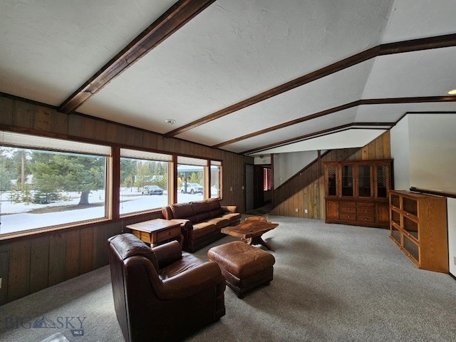 carpeted living area with vaulted ceiling with beams, a textured ceiling, and wooden walls