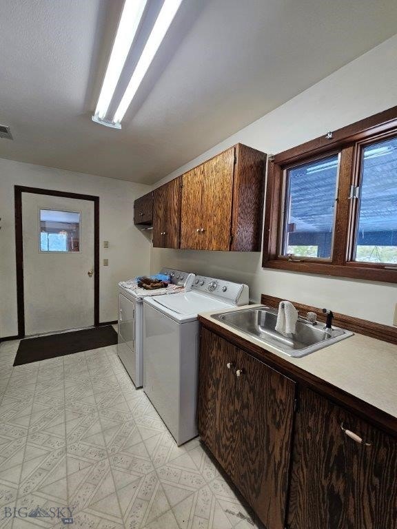 laundry room featuring cabinet space, visible vents, washing machine and clothes dryer, light floors, and a sink