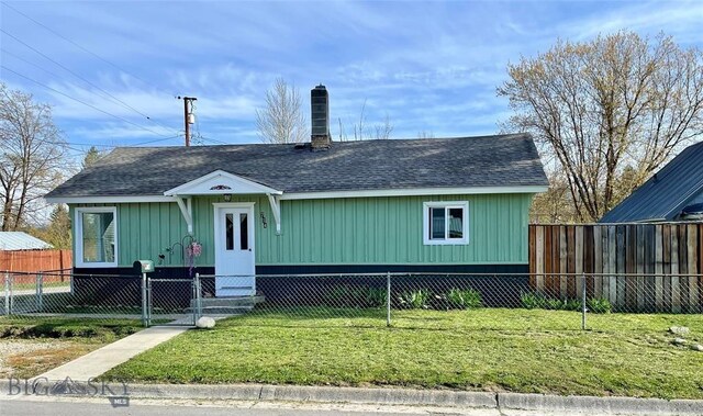 view of front of home featuring a fenced front yard, a front yard, roof with shingles, and a chimney