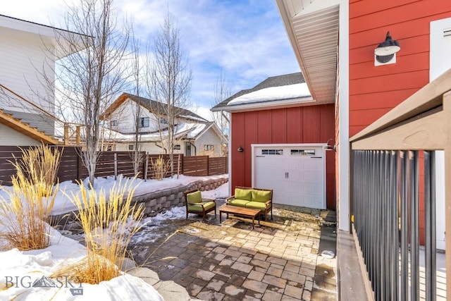 snow covered patio with a garage and fence