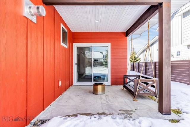 snow covered property entrance featuring a patio area