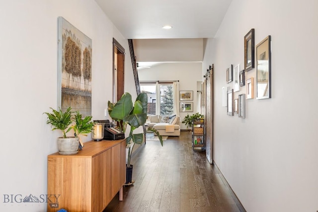 hall with dark wood-type flooring, recessed lighting, and a barn door