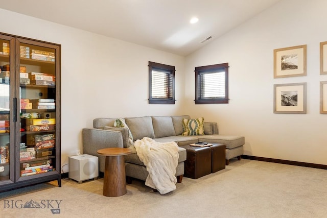 living area featuring vaulted ceiling, baseboards, visible vents, and light colored carpet