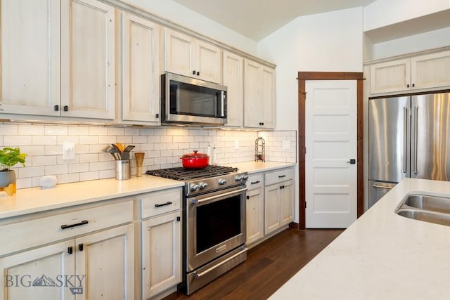 kitchen featuring tasteful backsplash, light countertops, dark wood-type flooring, and high quality appliances