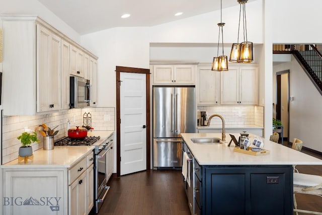 kitchen with a breakfast bar area, light countertops, appliances with stainless steel finishes, vaulted ceiling, and a sink