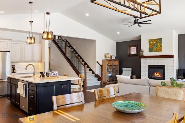 dining area with dark wood-style flooring, a fireplace, lofted ceiling, recessed lighting, and stairs