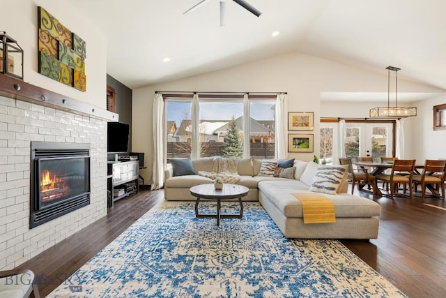 living area with dark wood-type flooring, a healthy amount of sunlight, and vaulted ceiling