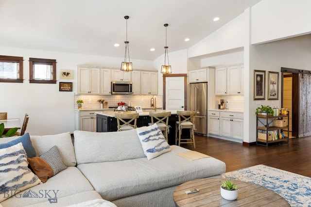 living room featuring high vaulted ceiling, dark wood-type flooring, a barn door, and recessed lighting