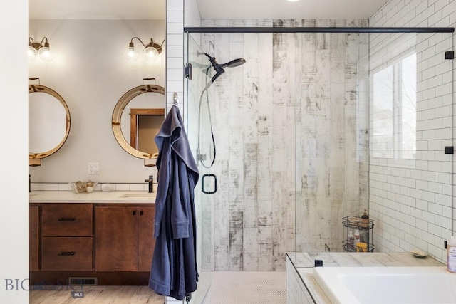 bathroom with a stall shower, visible vents, a washtub, vanity, and tile walls